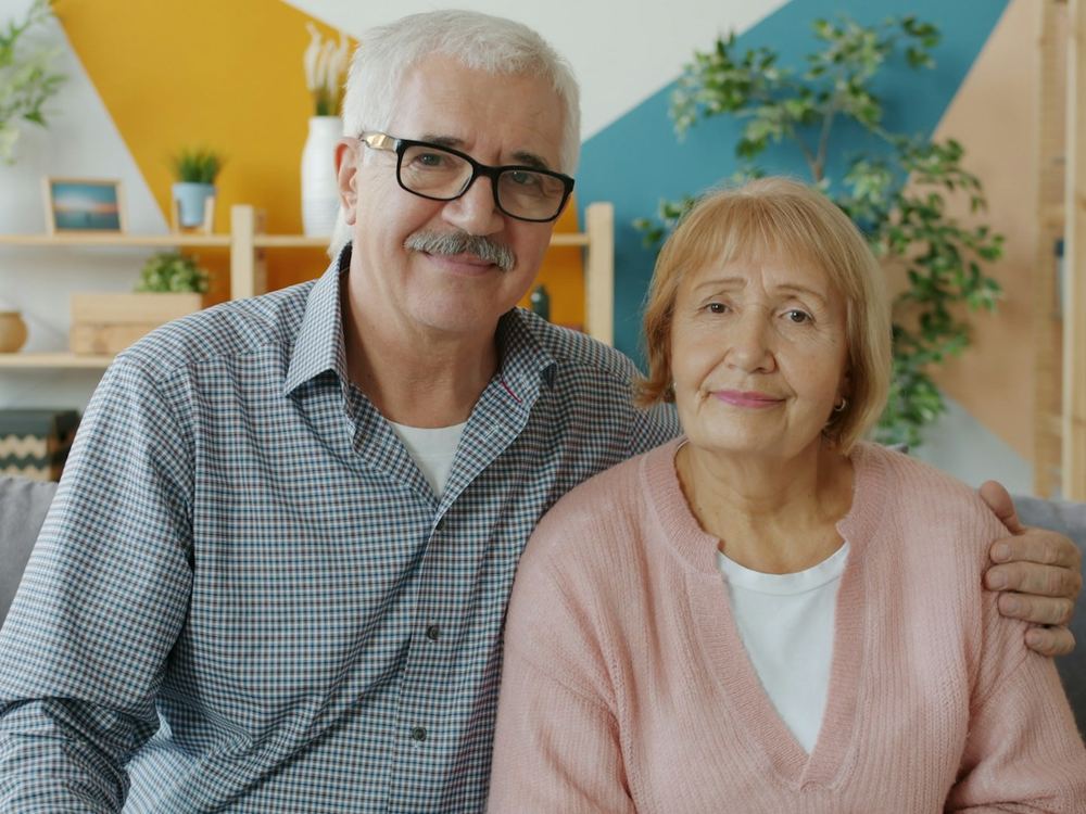 Älterer Mann und ältere Frau sitzen zufrieden nebeneinander auf dem Sofa